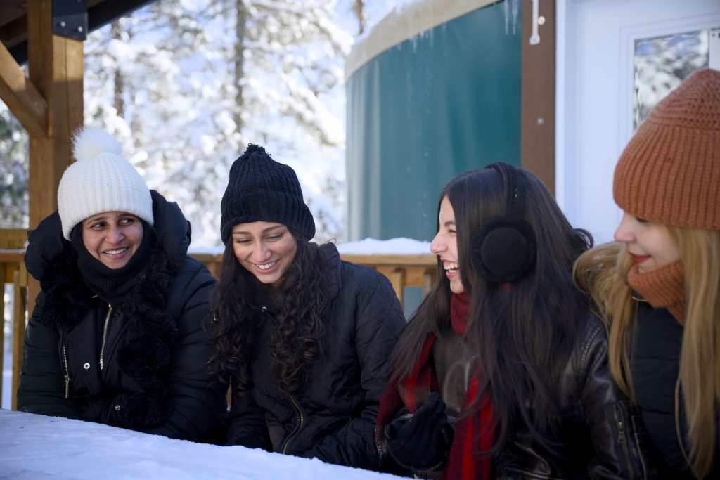 friends sitting at picnic table outside of yurt
