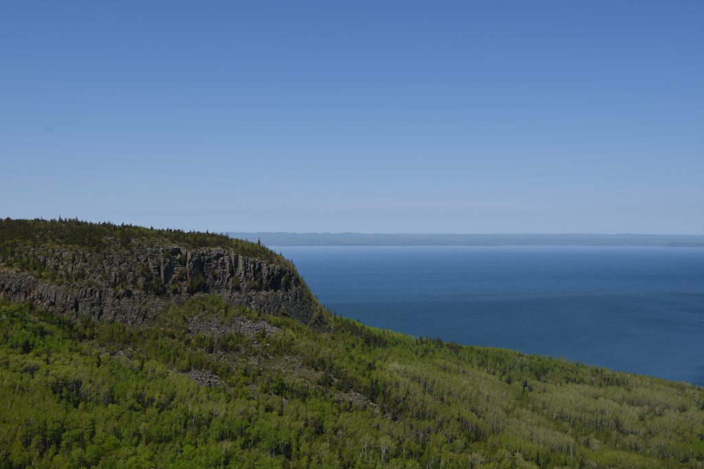 rocky cliffs peeking out from forest, overlooking lake
