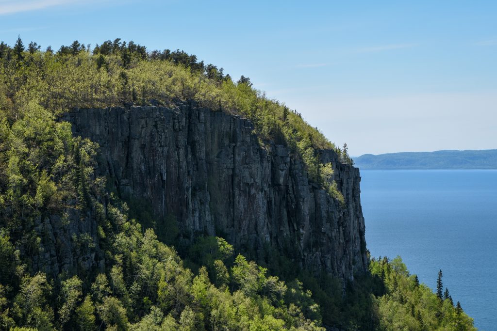 close up of cliffs with trees atop,  looking out to lake