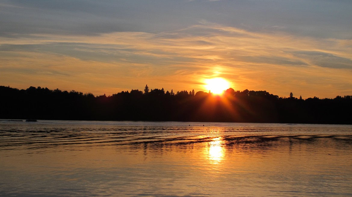 lake with sun setting over silhouetted treeline
