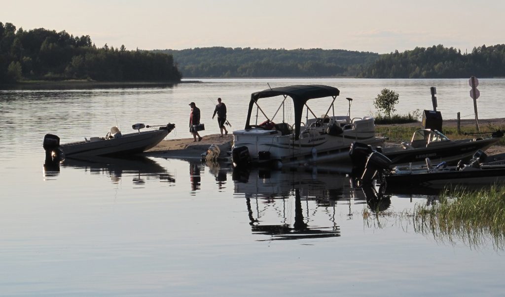 two people walking towards boat on shoreline of lake