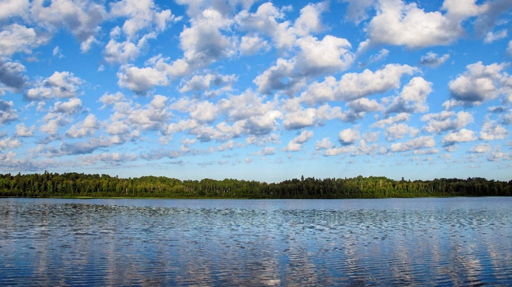 lake with blue sky filled with white, fluffy clouds