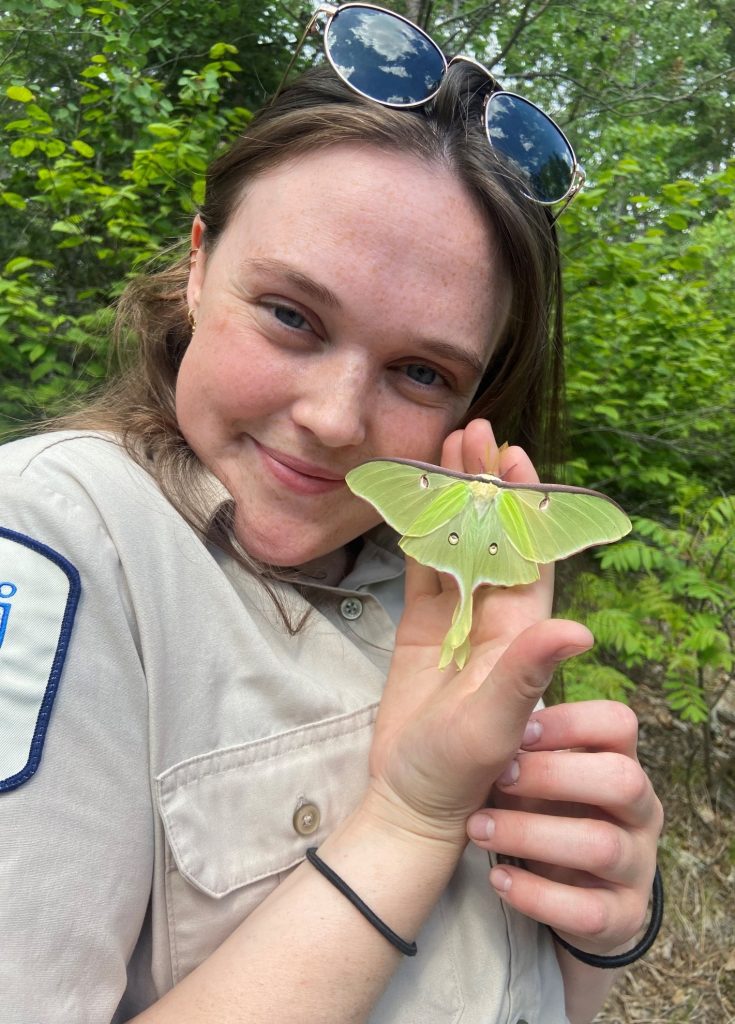 Kate holding Luna Moth in hand beside face
