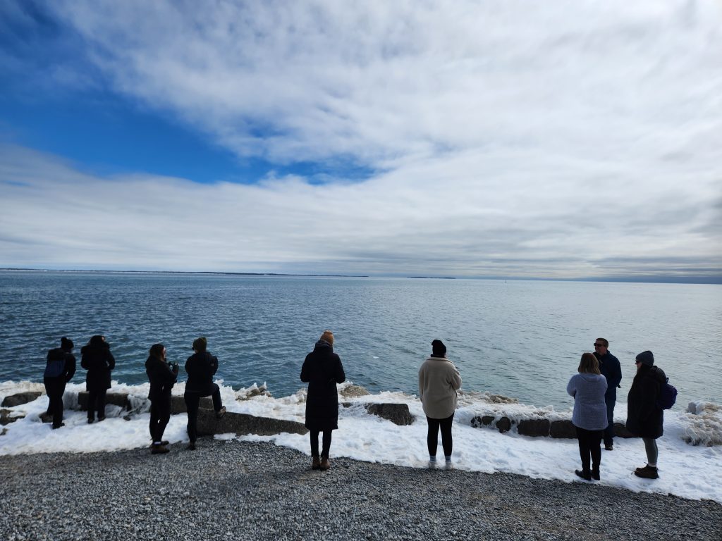 group of visitors on snowy shore of lake
