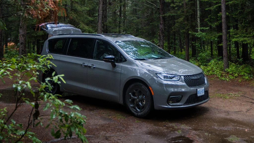 Car on campsite with trunk popped, potholes and puddles can be seen on ground