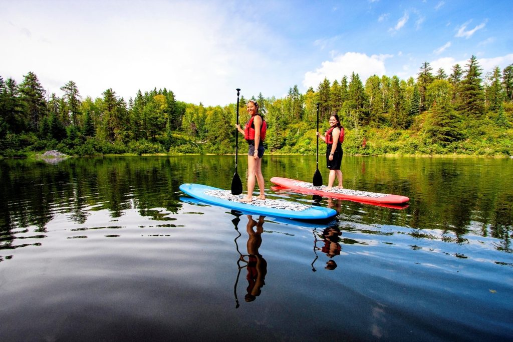 two people stand-up paddleboarding on lake