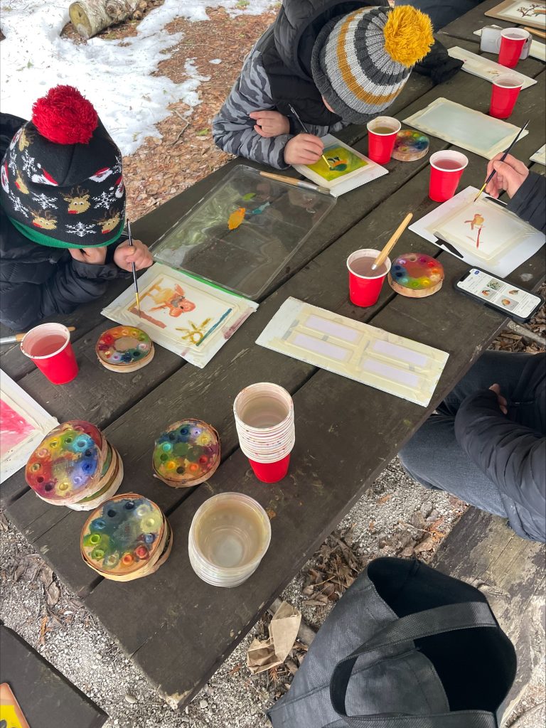 kids doing watercolour paintings on picnic table