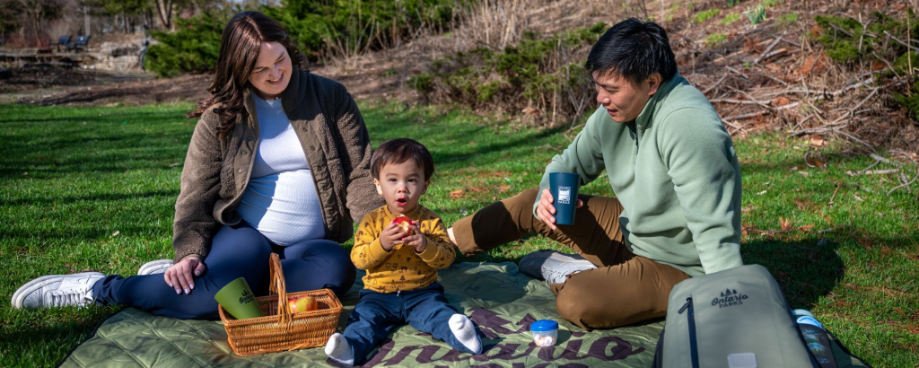 Des membres d’une famille assis sur une couverture de pique-nique, profitant d’un repas en plein air.