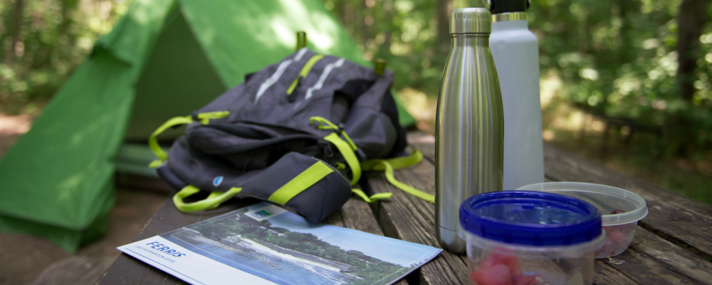 water bottles, backpack, plastic containers, and park tabloid on picnic table