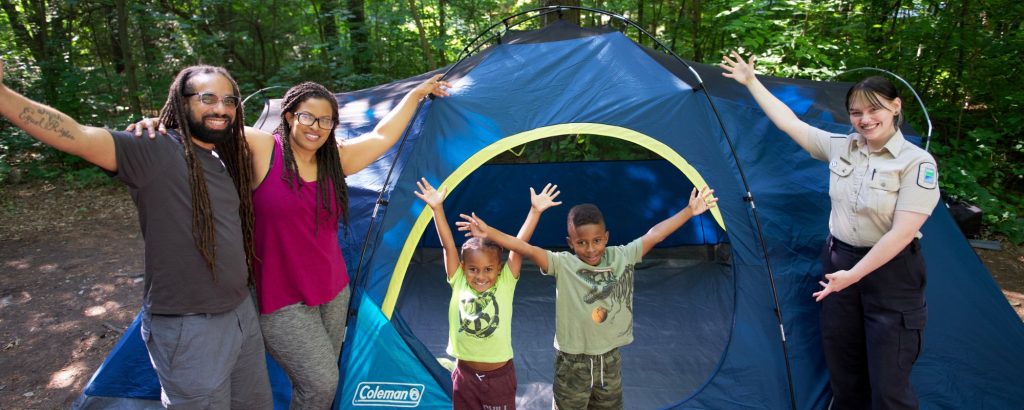 family and staff arms outstretched in front of tent