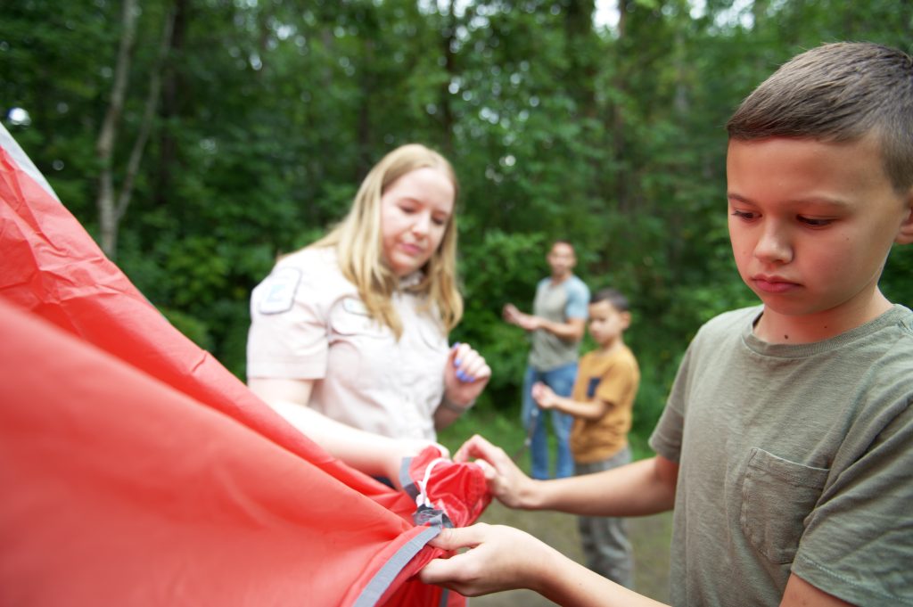 staff watching over child putting up tent