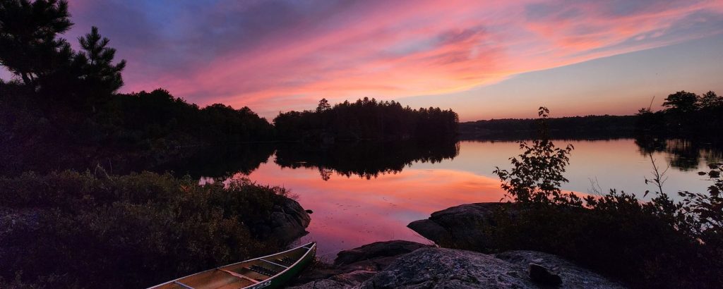 canoe on rocky lakeshore at sunset