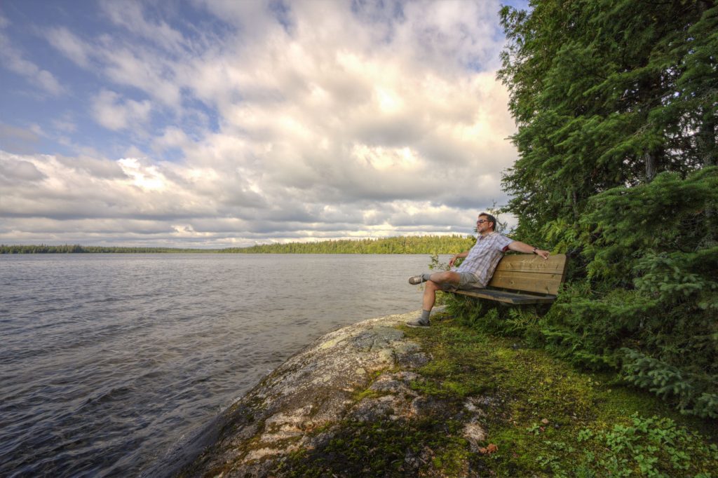 person sitting on bench looking out at lake