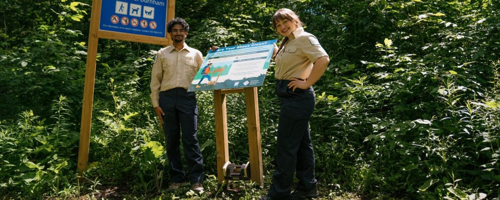park staff standing in front of boot brush station at trailhead