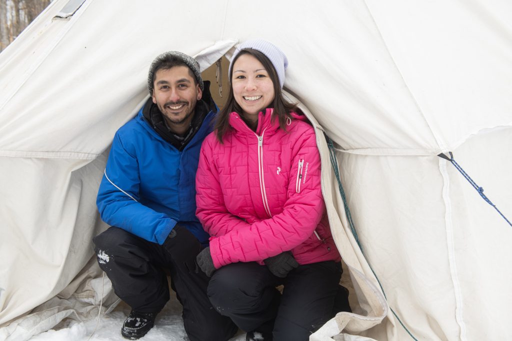 couple sitting outside of hot tent